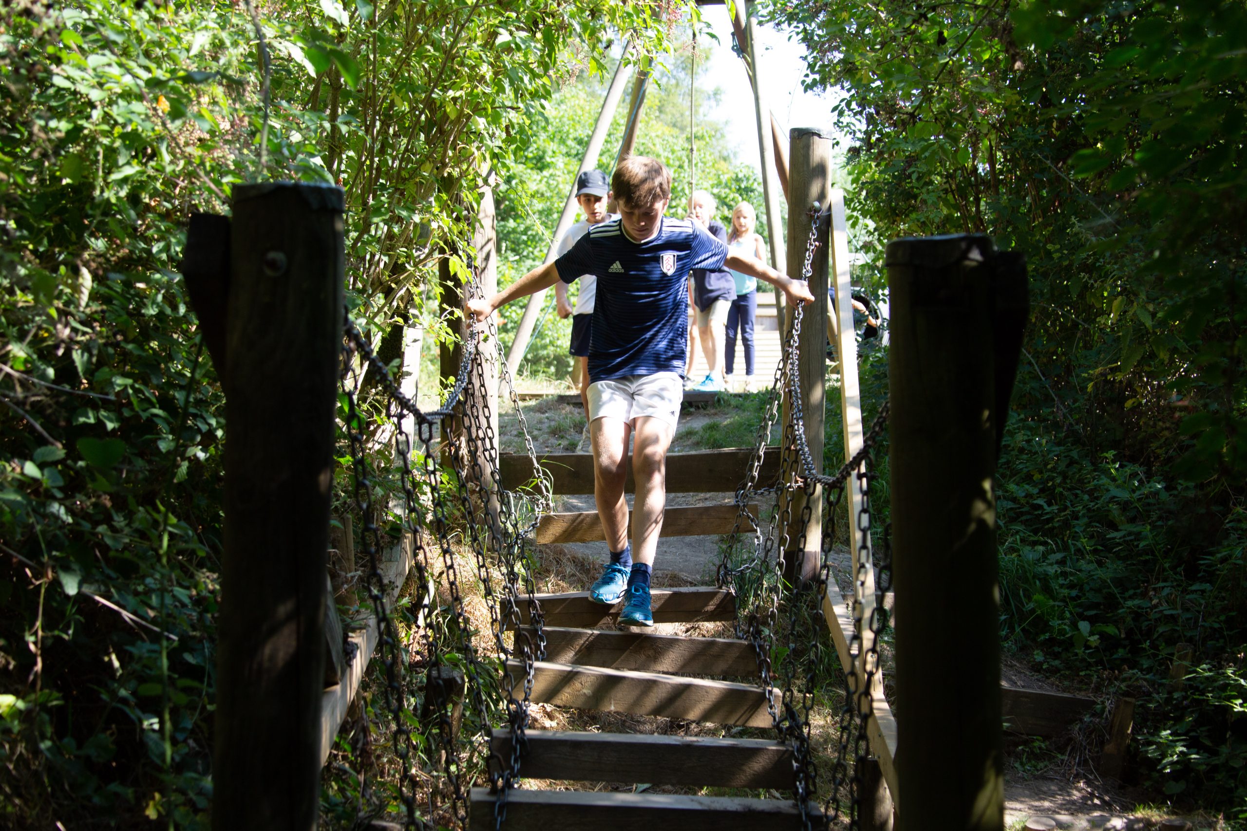 Students run across a wooden bridge.