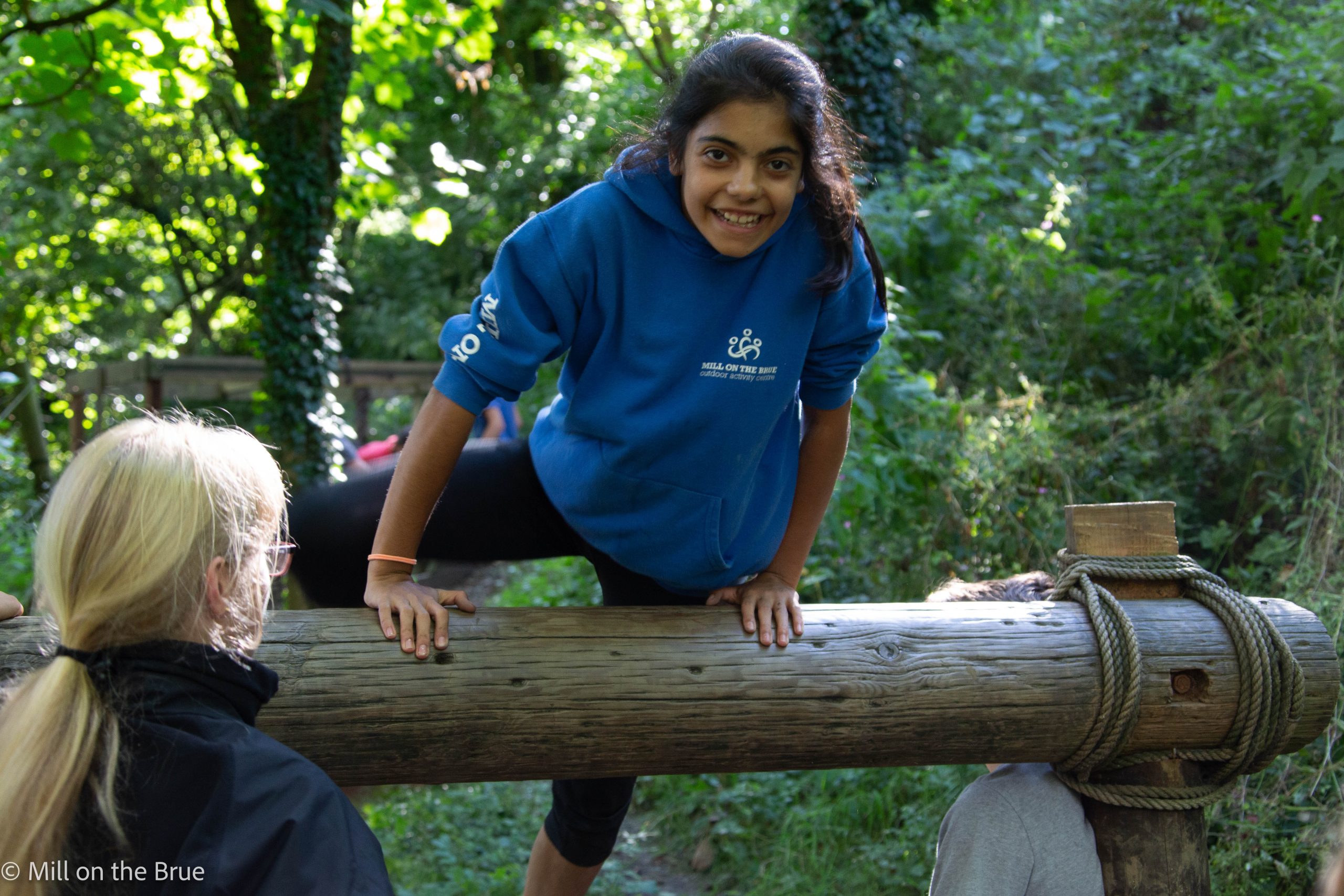 Child climbs over a log.