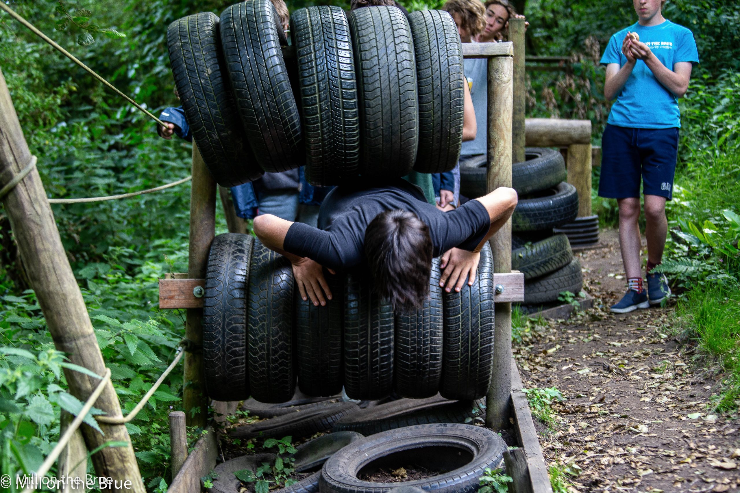 Child climbs through an obstacle course made of tyres.