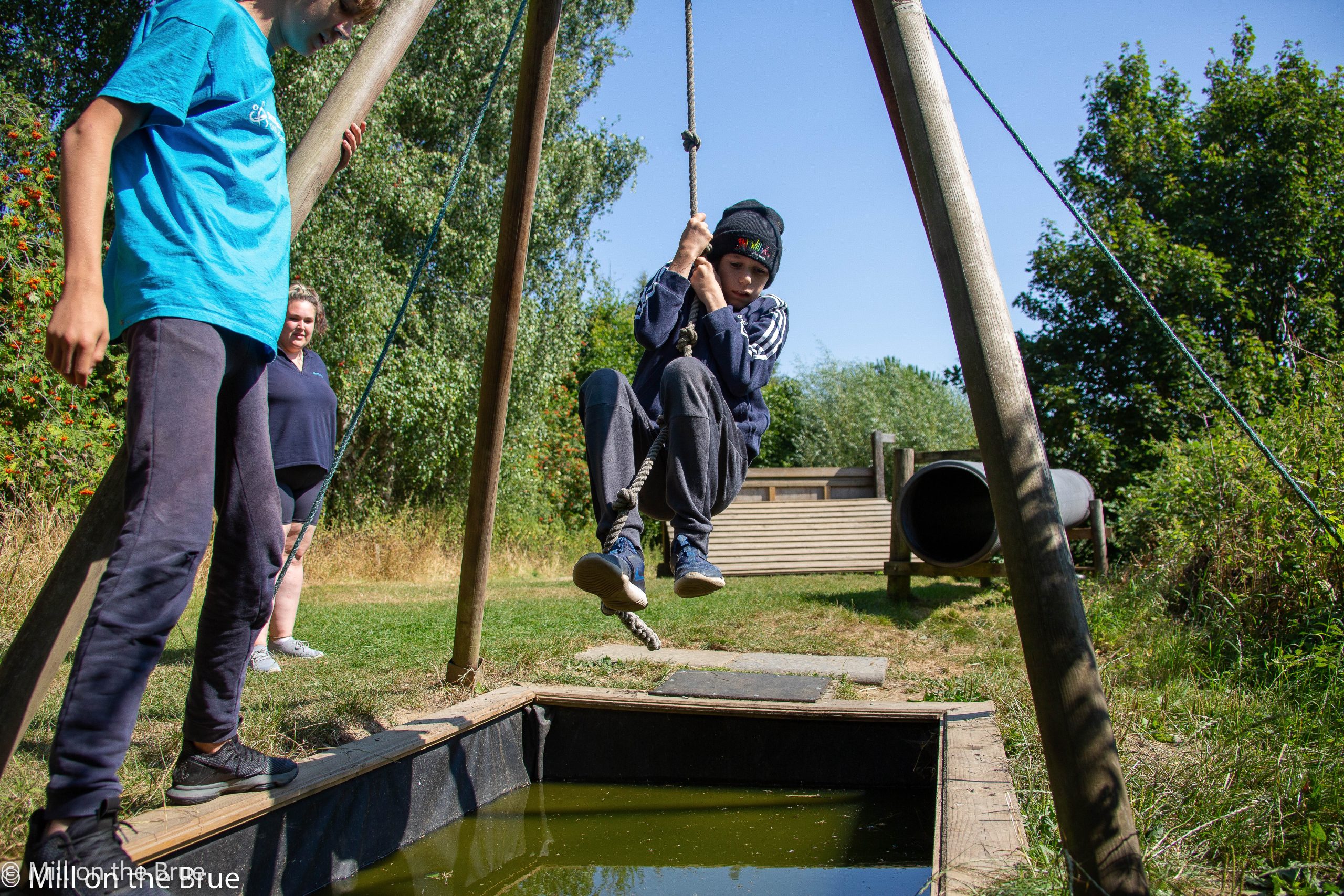 Child swings on a rope over water.