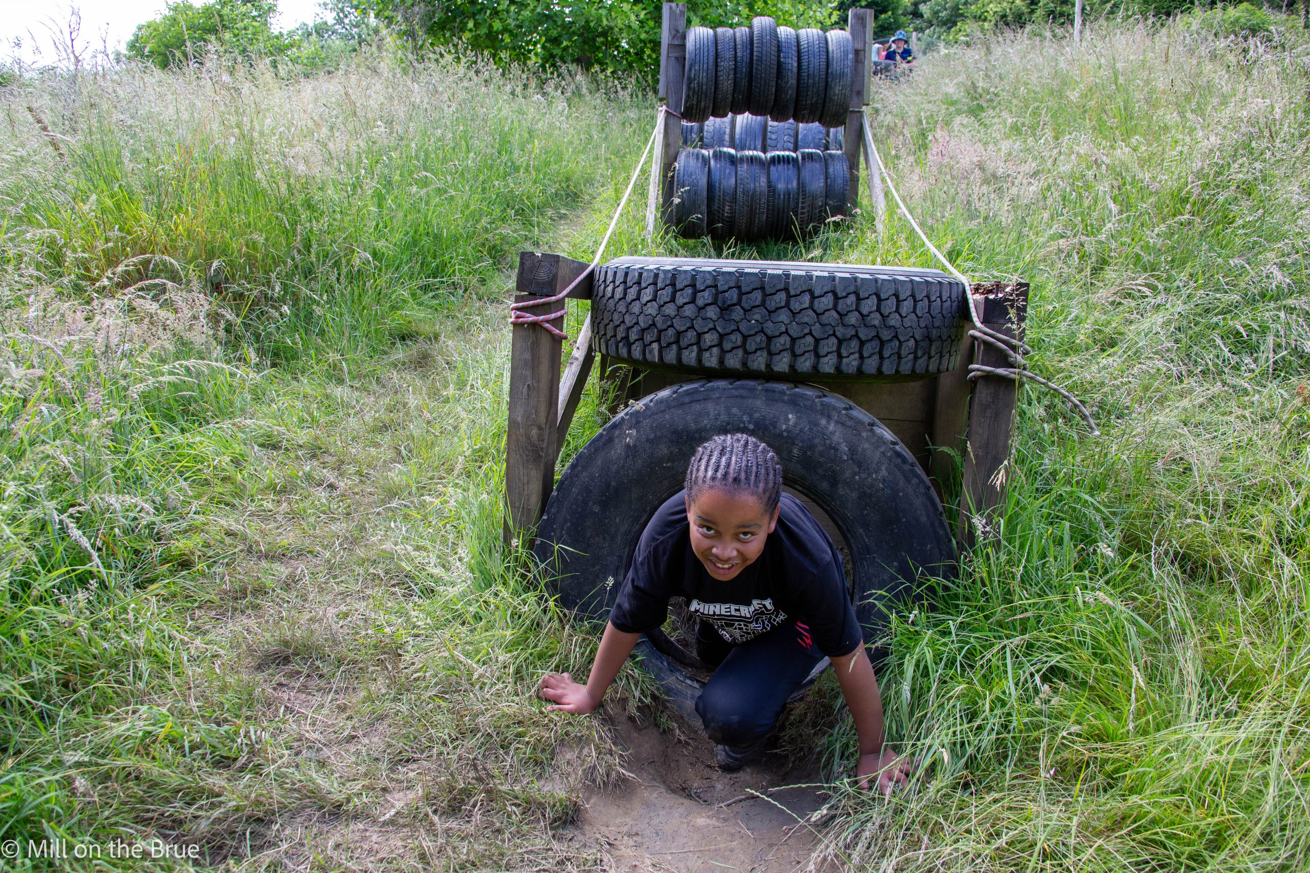 Child climbs through an obstacle course made of tyres.