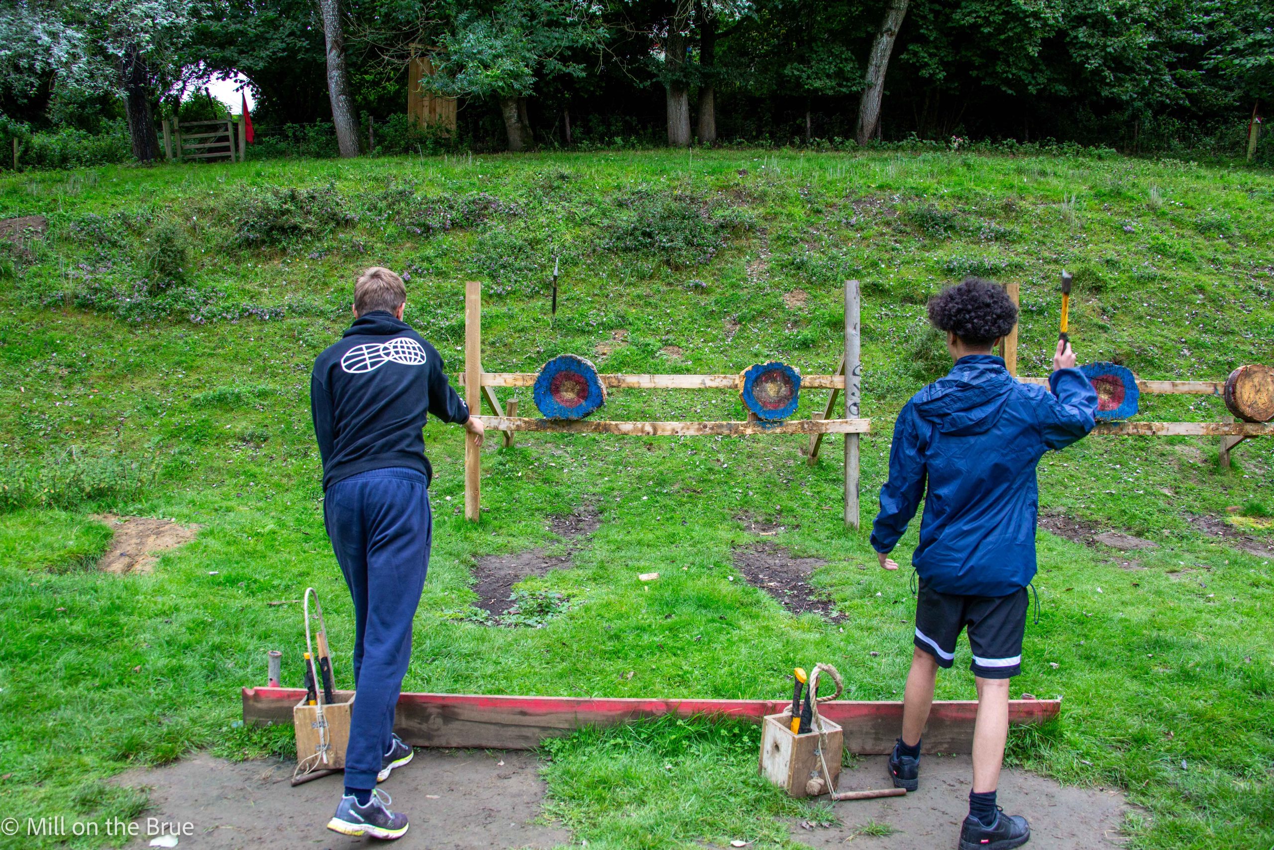 Teens throw axes at targets.
