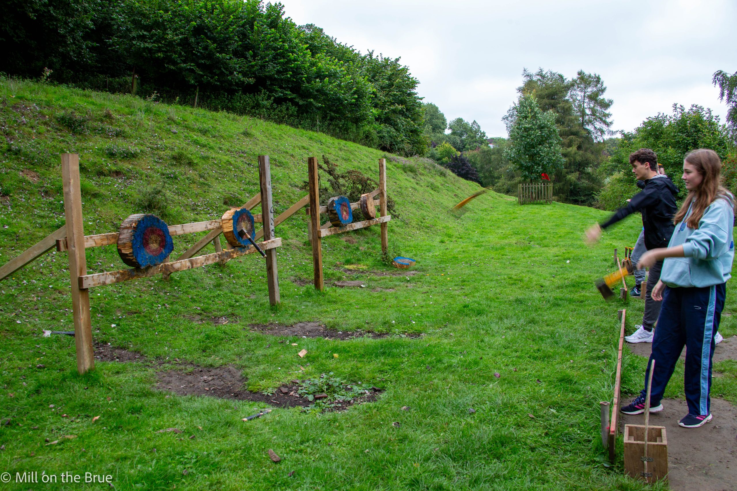 Teens throw axes at targets.
