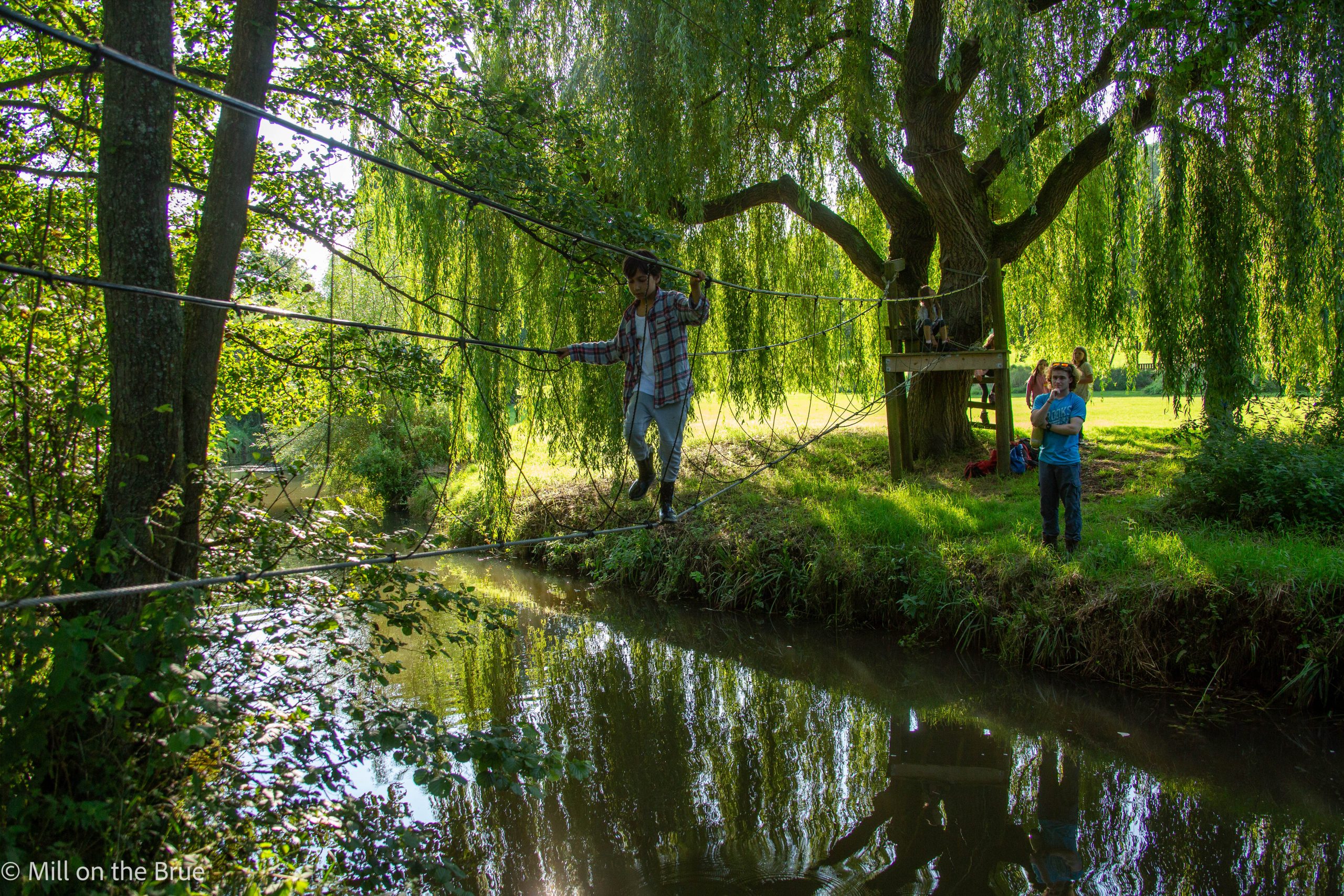 Child crosses a river on a rope bridge.