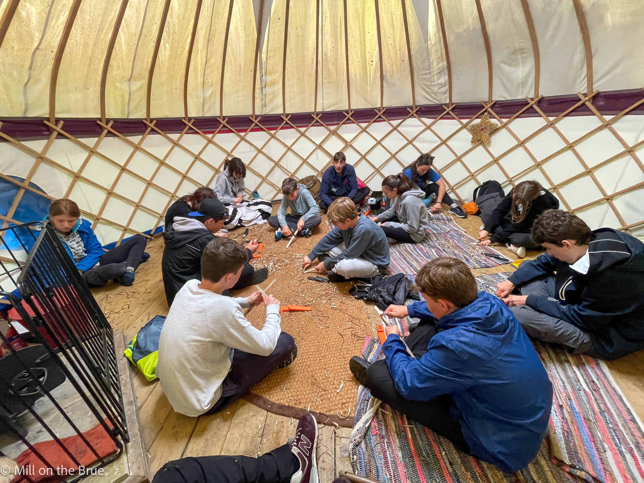 Students whittling in a yurt.