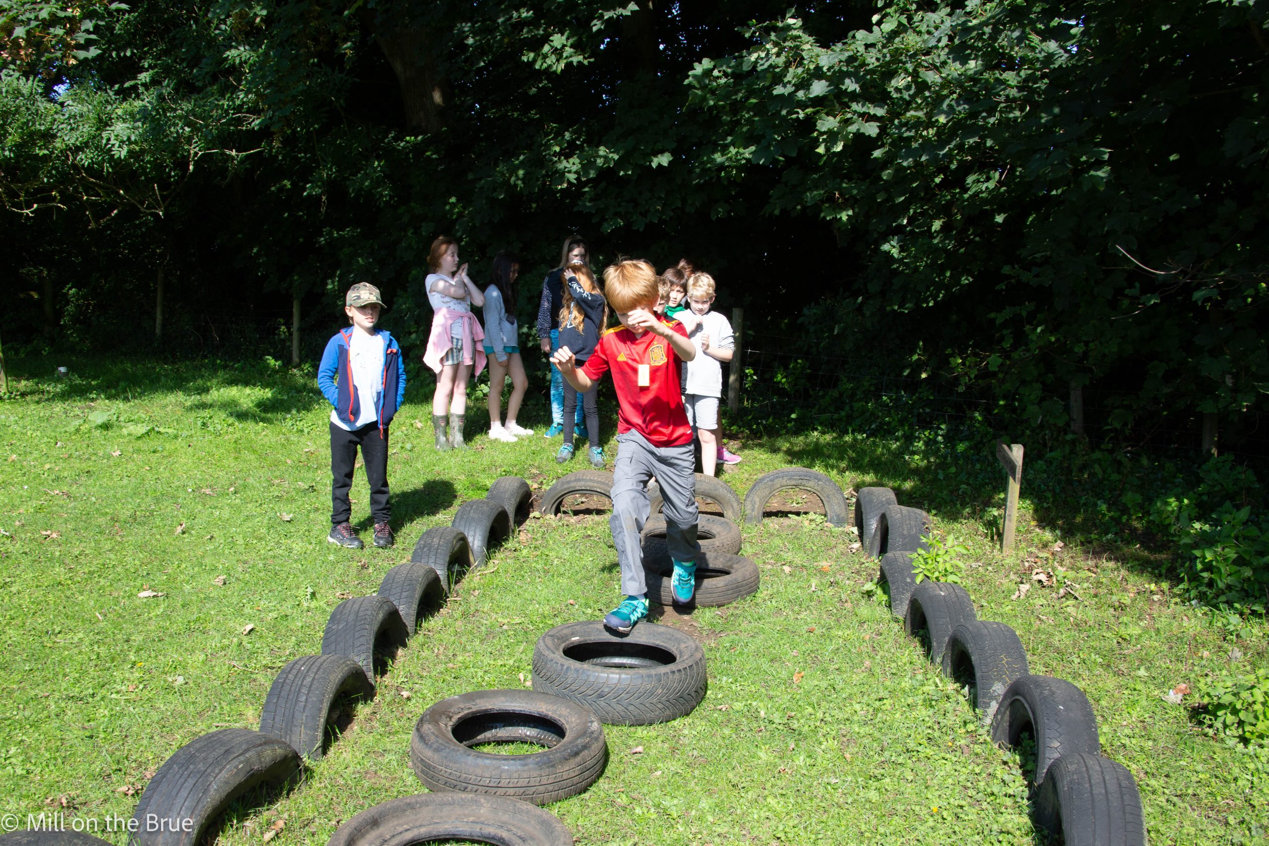 Children run across a row of tyres.