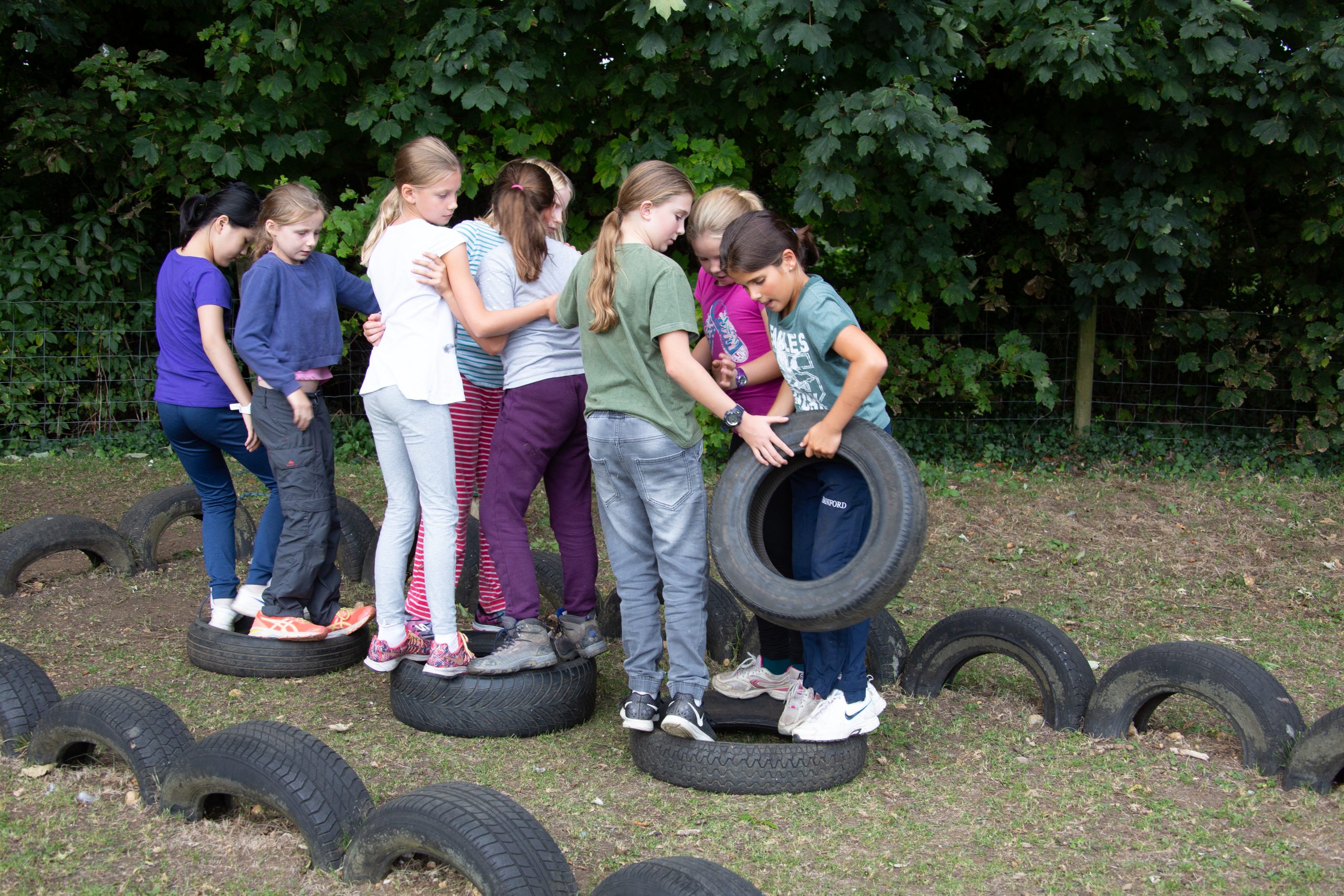 Children balance on a row of tyres.