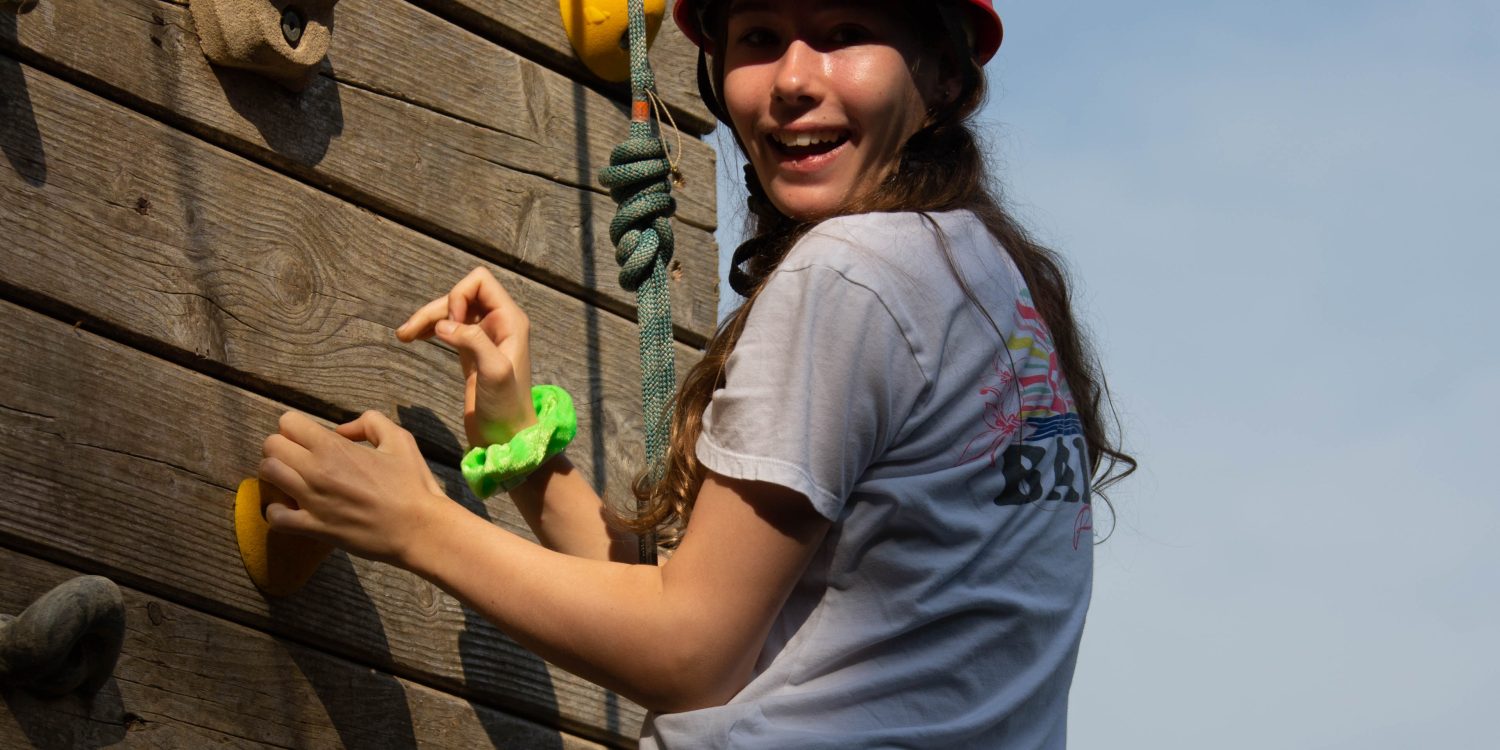 Teen on a wooden climbing wall.