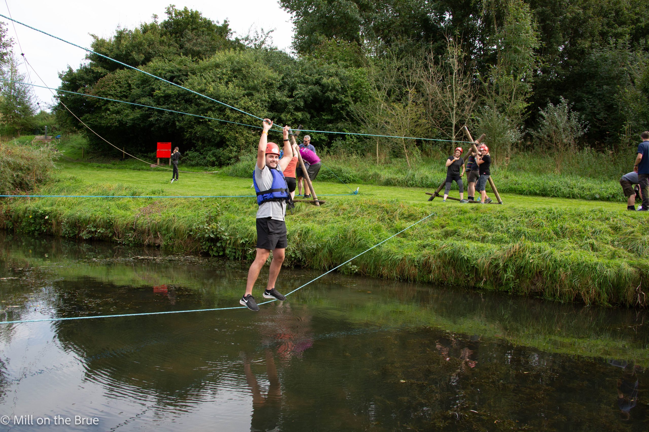 Man crosses river on rope bridge.