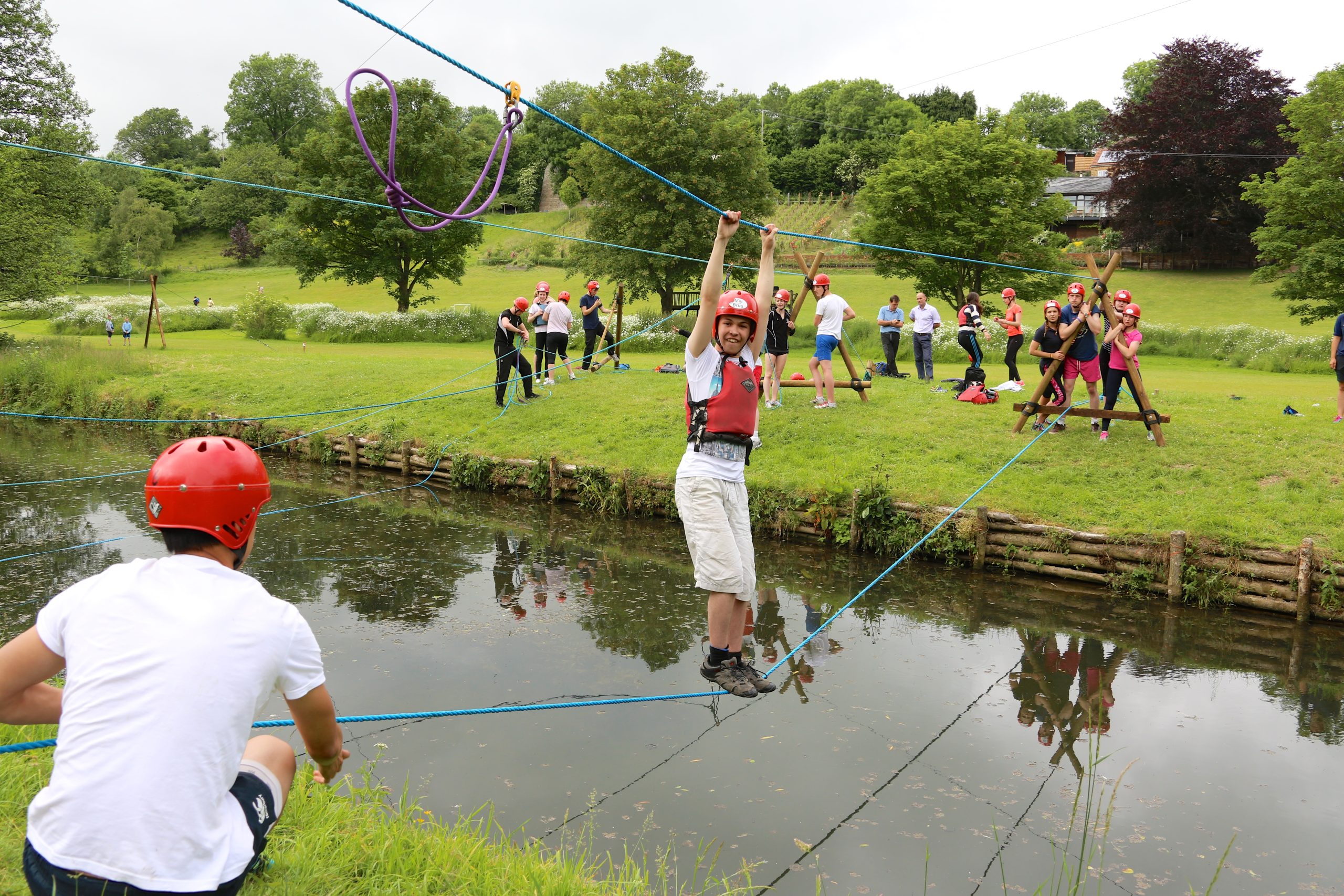 Student crosses river on rope bridge.