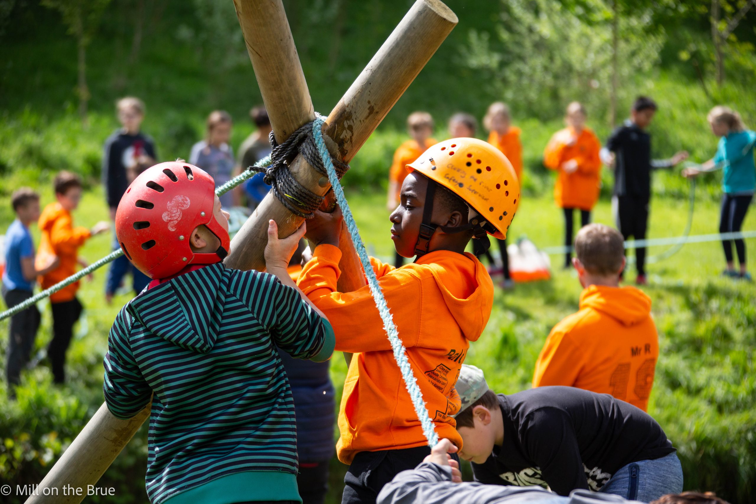 Children lifting wooden poles.