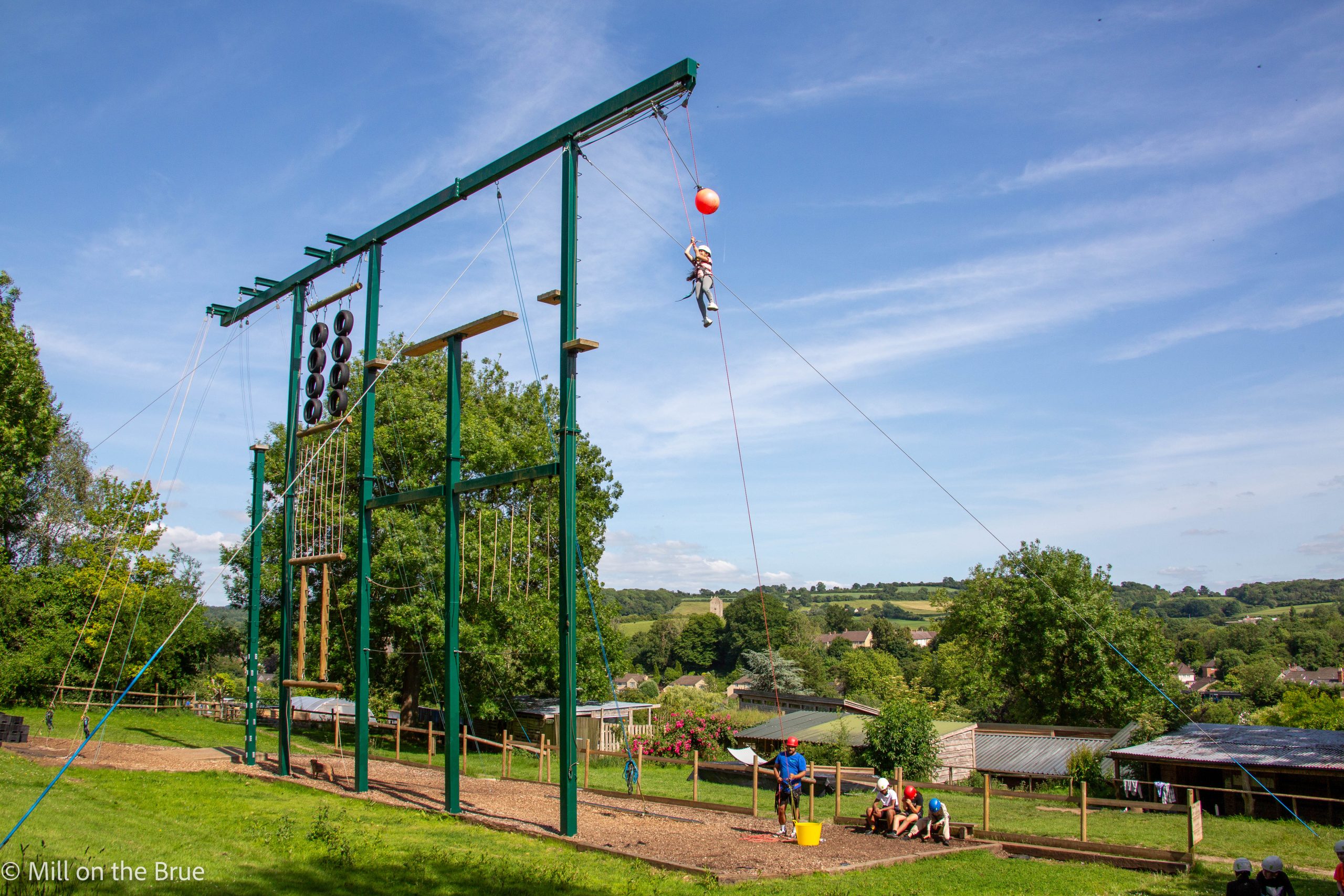 A student leaps through the air suspended on ropes.