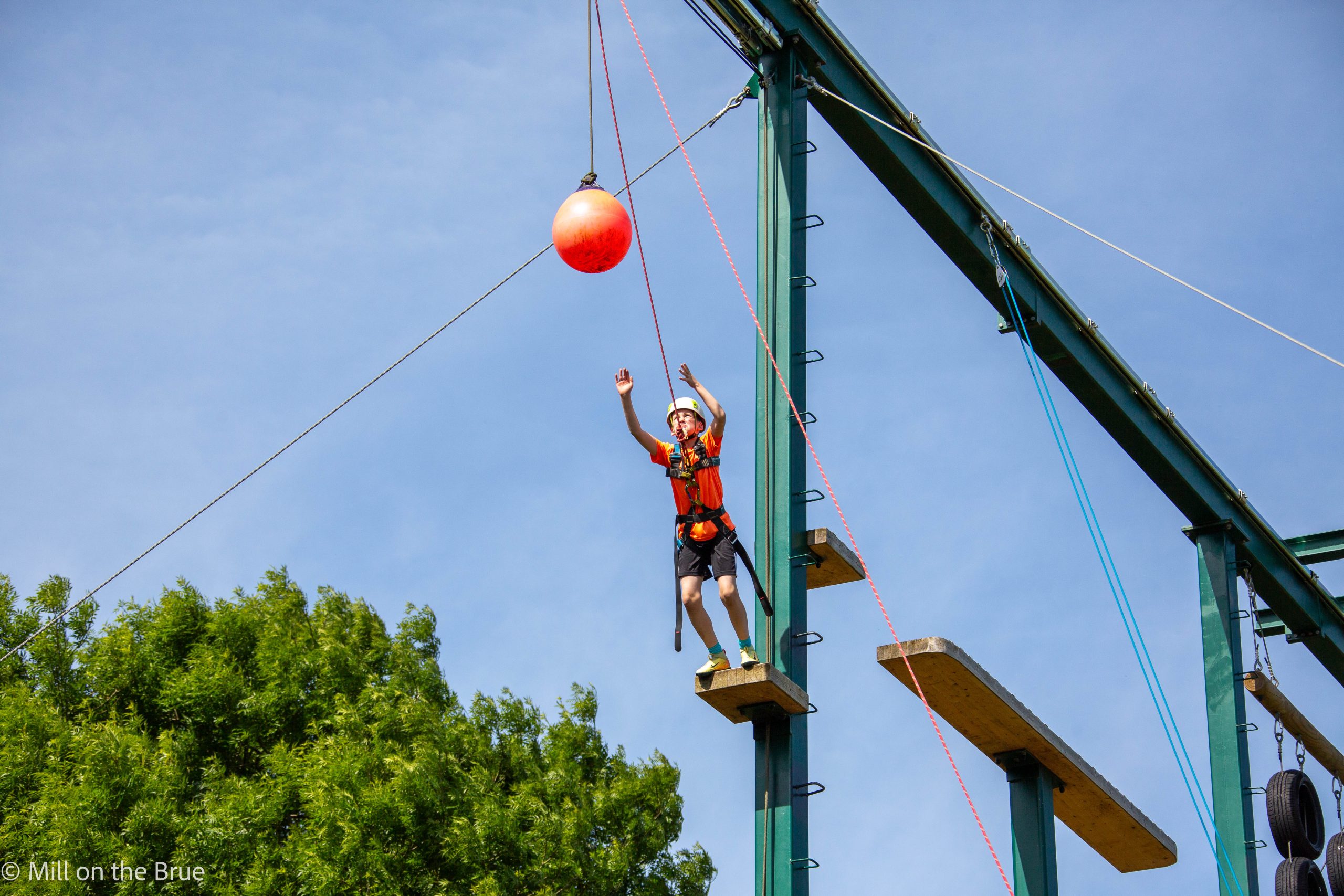 A student leaps through the air suspended on ropes.