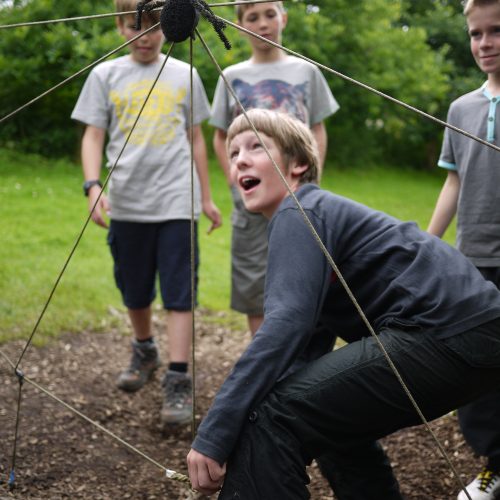 Student climbs through a giant spiderweb.