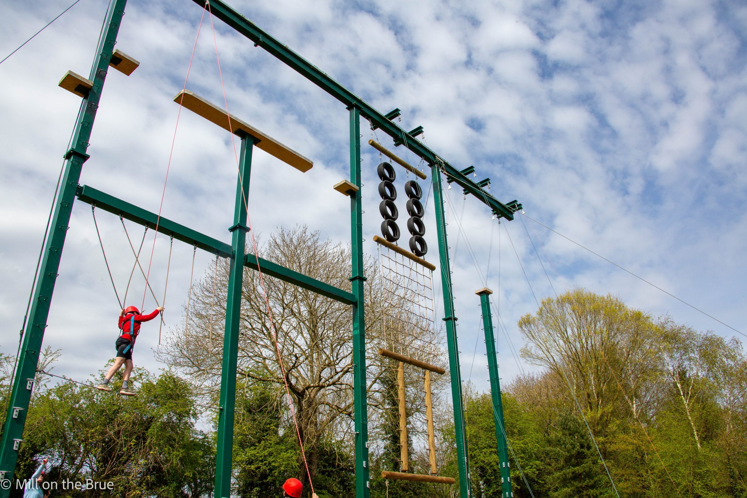 A child scales a large suspended obstacle course.