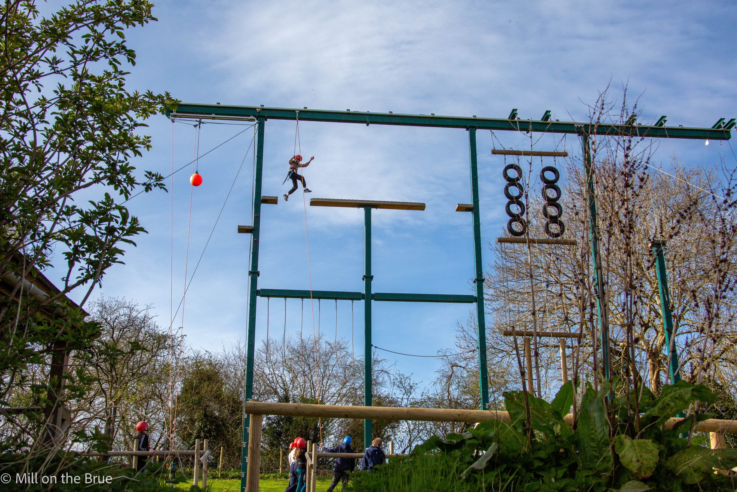 A child scales a large suspended obstacle course.