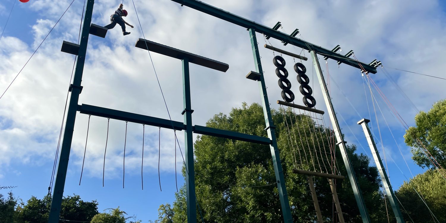 A child scales a large suspended obstacle course.