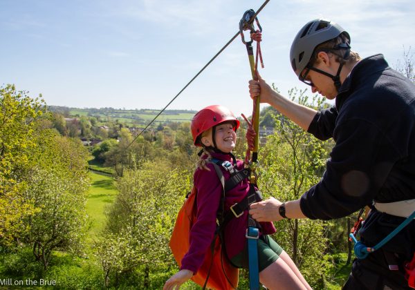 Instructor checks a child's safety harness before zip wire ride.